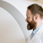 Médico ao lado de um aparelho de ressonância magnética