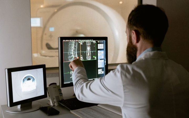 Médico analisando imagens de ressonância magnética da coluna em monitores