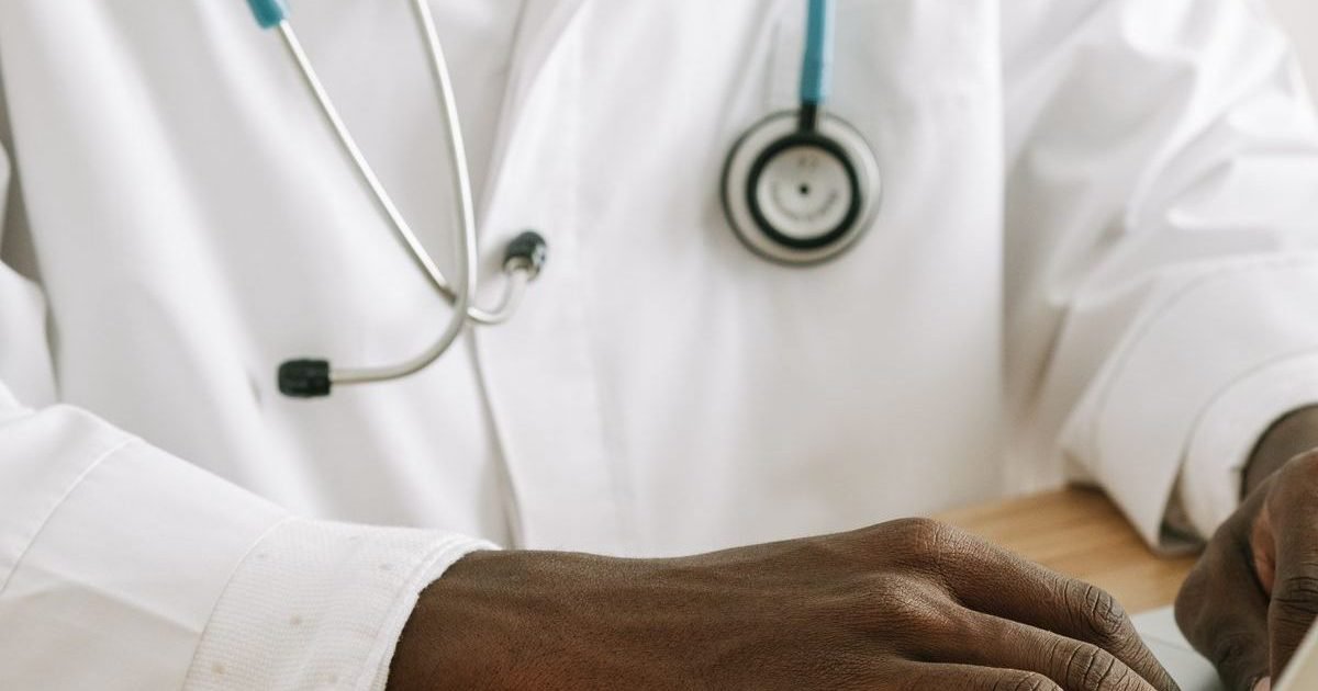 Médico de jaleco e estetoscópio trabalhando em um notebook