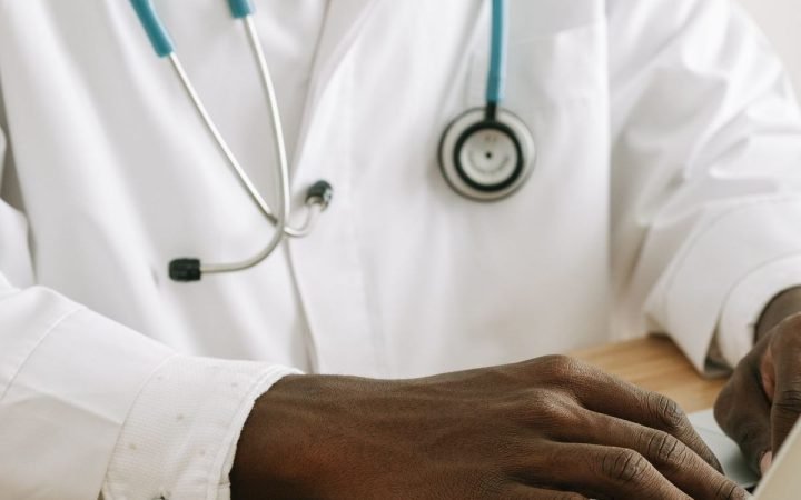 Médico de jaleco e estetoscópio trabalhando em um notebook